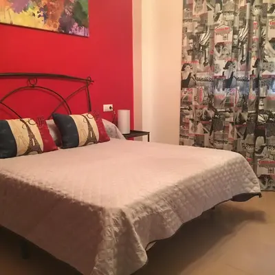 a bedroom with a bed with a red wall at Playa de Las Piletas in Sanlúcar de Barrameda