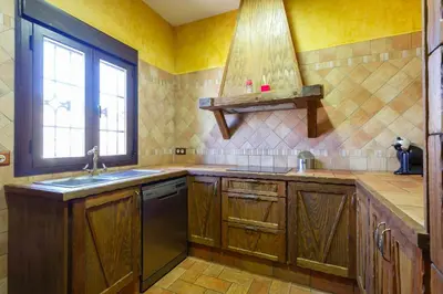 a kitchen with wooden cabinets and a sink and a window at El Castillito in Chiclana de la Frontera