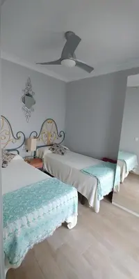 a room with two beds and a ceiling fan at Apartamento Solis in Chipiona