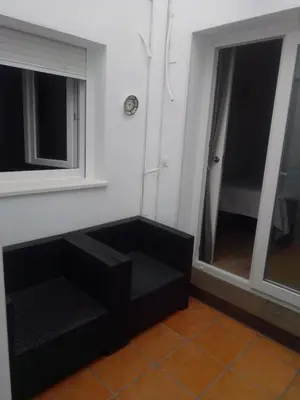 a room with two windows and a black couch at Apartamento Solis in Chipiona