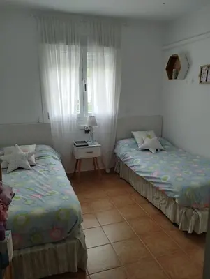 a bedroom with two beds and a table and a window at Frente al mar in Rota
