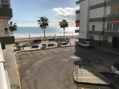 a parking lot next to a beach with palm trees at Frente al mar in Rota