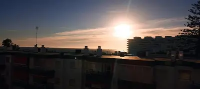 a sun is setting over a city with buildings at Frente al mar in Rota