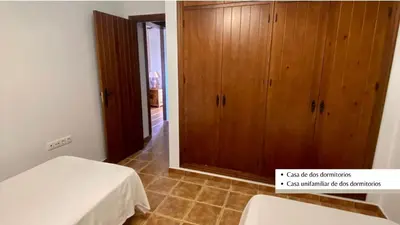 a bedroom with a bed and a wooden cabinet at Arco Casas Adosadas in Conil de la Frontera