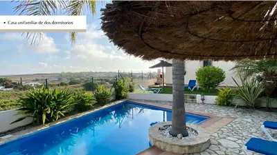 a swimming pool with a straw umbrella and a resort at Arco Casas Adosadas in Conil de la Frontera