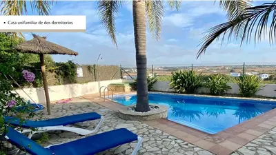 a villa with a swimming pool and palm trees at Arco Casas Adosadas in Conil de la Frontera