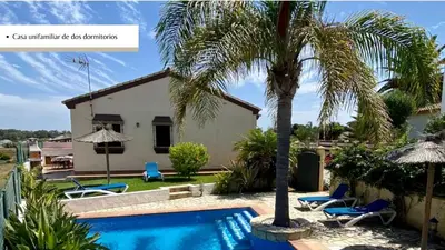 a villa with a swimming pool and a palm tree at Arco Casas Adosadas in Conil de la Frontera