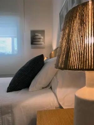 a bed with two pillows and a lamp on a table at Apartamento en la playa de Valdelagrana in El Puerto de Santa María