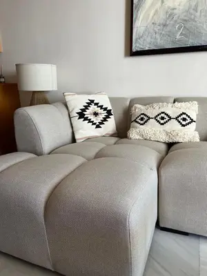 a couch with two pillows on it in a living room at Apartamento en la playa de Valdelagrana in El Puerto de Santa María