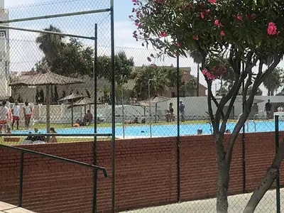 a fence next to a swimming pool with a tree at Apartamento en la playa de Valdelagrana in El Puerto de Santa María