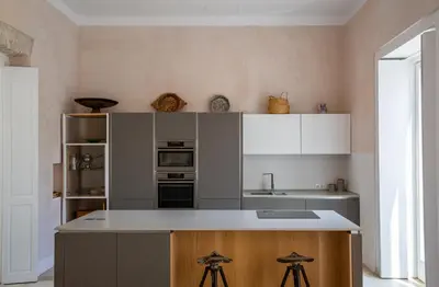 a kitchen with white cabinets and a counter with stools at Casa Plaza San Antonio in Cádiz