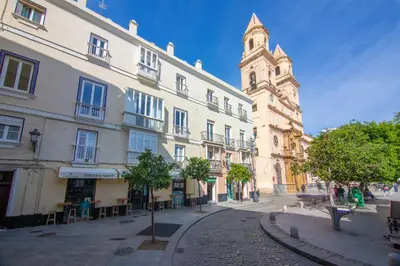a large building with a clock tower on a street at Casa Plaza San Antonio in Cádiz