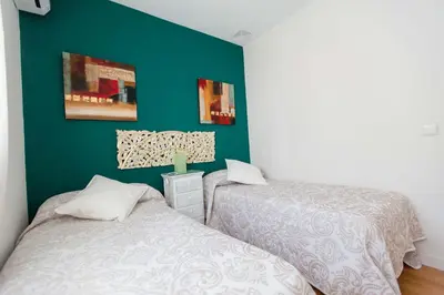 a bedroom with two beds and a green wall at Atico Centro Historico in Cádiz