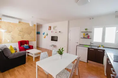 a living room with a white table and a kitchen at Atico Centro Historico in Cádiz