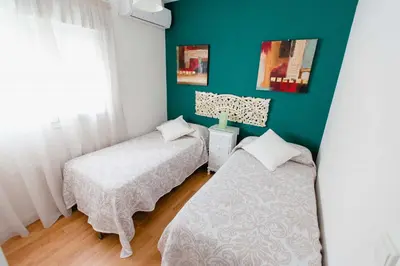 a bedroom with two beds and a green wall at Atico Centro Historico in Cádiz
