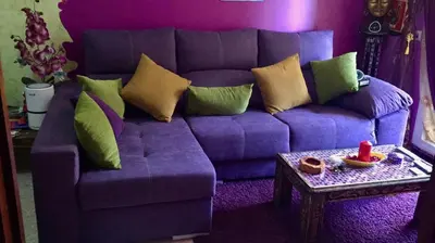 a purple couch with pillows and a table in a living room at La Casita Del Indio in Sanlúcar de Barrameda