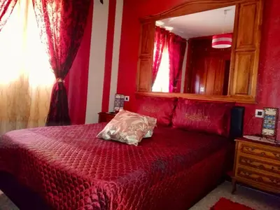 a red bedroom with a bed and a mirror at La Casita Del Indio in Sanlúcar de Barrameda