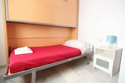 a bed in a room with a red blanket and a night stand at Apartamento VELADOR del Sur by Cadiz4Rentals in Cádiz