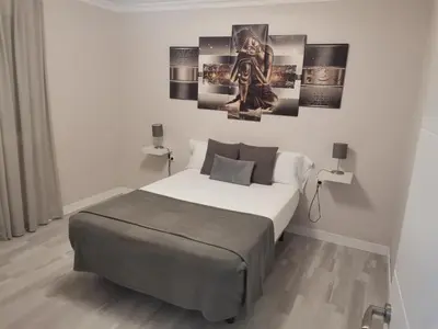 a bedroom with a bed and some pictures on the wall at Casasjerezanas Mariposa in Jerez de la Frontera