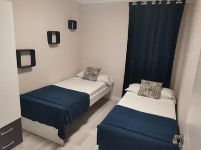 two beds in a room with blue curtains at Casasjerezanas Mariposa in Jerez de la Frontera