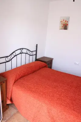 a bedroom with a bed with a red comforter at Casa Rural El Limonero in Los Naveros