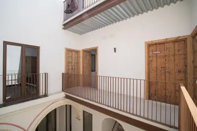 a room with a balcony and wooden doors at Apartamentos Alcoba 13 in Sanlúcar de Barrameda
