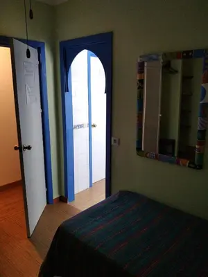 a bedroom with a door and a mirror and a bed at El apartaito in Sanlúcar de Barrameda