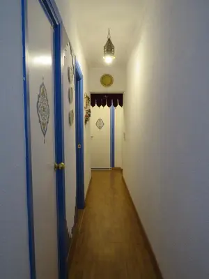 a long hallway with blue doors and a wooden floor at El apartaito in Sanlúcar de Barrameda