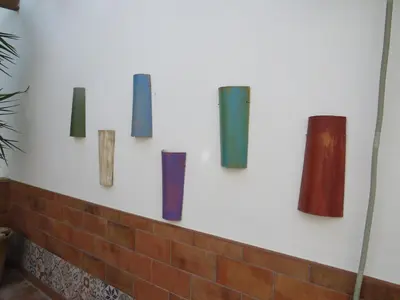 a group of different colored vases on a wall at El apartaito in Sanlúcar de Barrameda