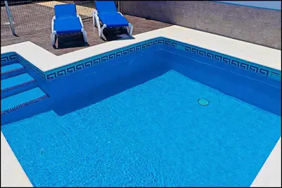 two chairs and a swimming pool with blue water at Casa Rural Zara II in Conil de la Frontera