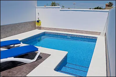 a swimming pool with a chair and a table and a blue poolvisor at Casa Rural Zara II in Conil de la Frontera