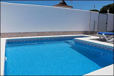 a swimming pool with a chair next to a white wall at Casa Rural Zara II in Conil de la Frontera