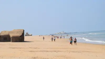 a group of people walking on the beach at Emperador Carlos in San Fernando