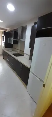 a kitchen with a white refrigerator and black cabinets at Emperador Carlos in San Fernando