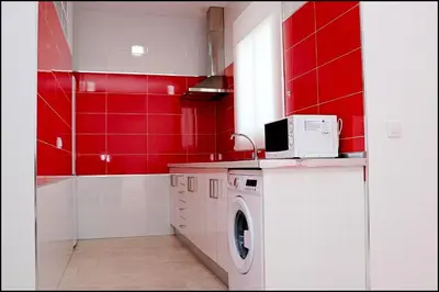 a kitchen with red walls and a washing machine at Casa Rural Zara I in Conil de la Frontera