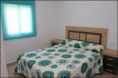 a bedroom with a bed with a floral bedspread and a window at Casa Rural Zara I in Conil de la Frontera