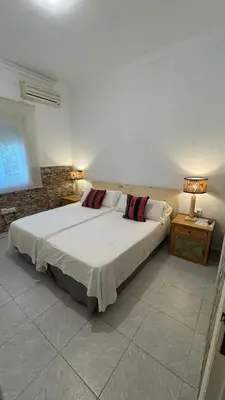 a bedroom with a large white bed with two lamps at Hostal Playa Hidalgo in Rota