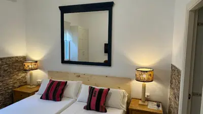 a bedroom with a white bed and a large mirror at Hostal Playa Hidalgo in Rota