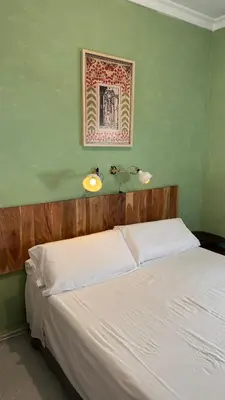 a bedroom with a white bed with a green wall at Hostal Playa Hidalgo in Rota