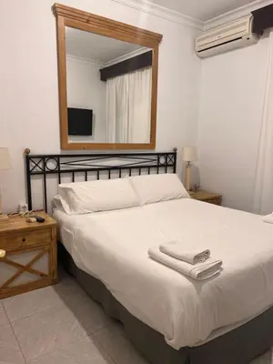 a bedroom with a large white bed with a mirror at Hostal Playa Hidalgo in Rota
