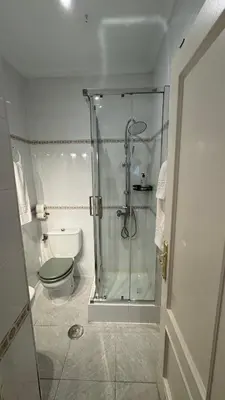 a bathroom with a toilet and a glass shower at Hostal Playa Hidalgo in Rota