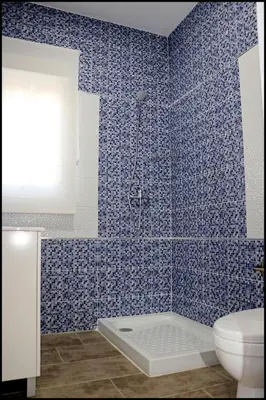 a blue tiled bathroom with a shower and a toilet at Casa Rural Zara III in Conil de la Frontera