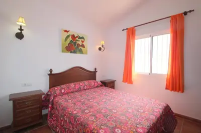 a bedroom with a bed and a window with orange curtains at Casa Jorge in Conil de la Frontera