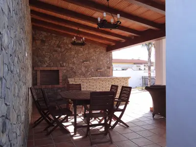a patio with a table and chairs and a stone wall at Casa Jorge in Conil de la Frontera