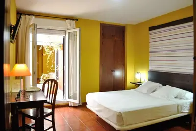 a bedroom with a bed and a desk and a window at Hostal La Andaluza in San Fernando