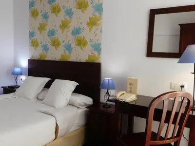a bedroom with a bed and a desk with a phone at Hostal La Andaluza in San Fernando