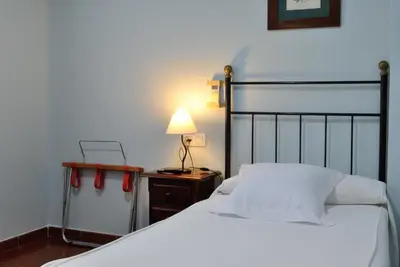 a bedroom with a bed and a lamp on a night stand at Hostal La Andaluza in San Fernando