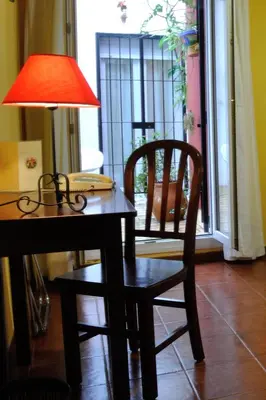 a table with a lamp and a chair next to a door at Hostal La Andaluza in San Fernando