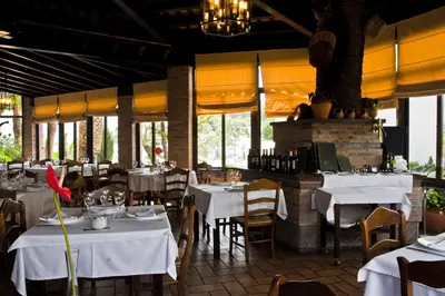 a restaurant with white tables and chairs and windows at Hotel Restaurante El Duque in Medina Sidonia