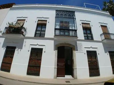 a white building with windows and doors on a street at Dúplex centro, climatizado, garaje, piscina, WIFI in Sanlúcar de Barrameda